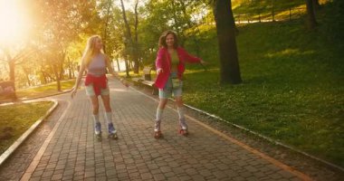 Halka açık parkta paten kayan iki günlük giysili kadın. Formda Güzel Bayanlar Sunrise 'da taşınıyor. Fitness Gençlik Kültür Çeşitliliği İnsanları.