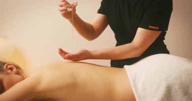 Spa Salonu 'nda yatakta uzanan ve masajdan zevk alan mutlu genç kadın. Kozmetikçi, lenfatik drenaj ve kaldırma efekti için kadın müşteriye masaj yağı döktü. Güzellik, Cilt Bakımı.