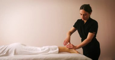 Spa Salonu 'nda yatakta uzanan ve masajdan zevk alan mutlu genç kadın. Lenfatik drenaj ve kaldırma efekti için kozmetik uzmanı kadın müşteriye masaj yapıyor. Güzellik, Cilt Bakımı