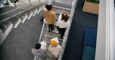 Profesyonellerden oluşan çeşitli ekipler merdivenlerden çağdaş ofise inerler. Çok ırklı işçiler, iş belgelerini içeren görüşmelere katıldılar