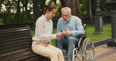 Genç bir kadın ve yaşlı bir adam parkta bankta oturmuş akıllı telefona bakıyor ve konuşuyorlar. Ortak ilgi ve bağlantı, nesiller arası boşlukları oluşturur.