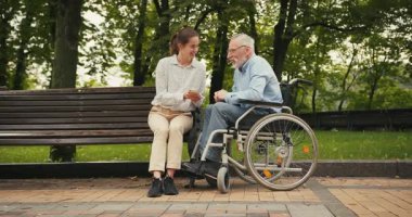 Genç bir kadın ve yaşlı bir adam parkta bankta oturmuş akıllı telefona bakıyor ve konuşuyorlar. Ortak ilgi ve bağlantı, nesiller arası boşlukları oluşturur.