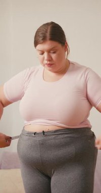 Ayrıca bel çevresindeki ölçü bandını tutan kadın aşağı bakıyor. Kadın, diyet döneminde vücut ölçüsünü kontrol ederken tatmin edici olmayan sonuçlara tepki verir