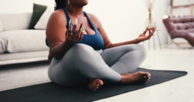 Gülümseyen ve iri yarı Afrikalı Amerikalı bir kadın aydınlık odada huzurlu bir yoga seansının keyfini çıkarıyor. Bayan kendini sevdirmeyi ve sağlıklı olmayı destekliyor. Vücut pozitifliğini kucaklıyor.