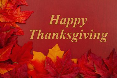 Happy Thanksgiving message with orange fall leaves on red wood clipart