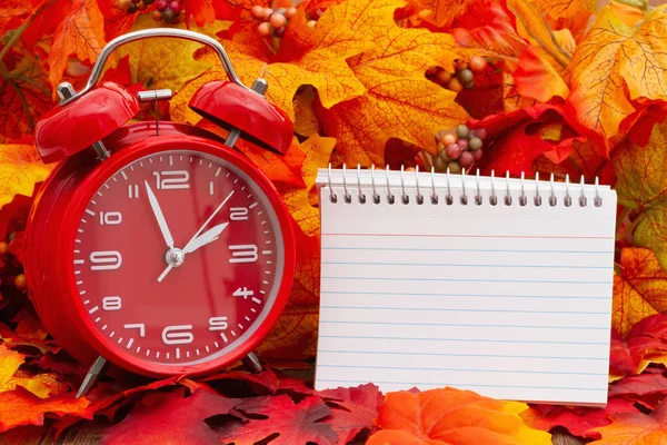 目覚まし時計付きの空白のメモ帳と秋の葉あなたの時間の変更や秋の時間のメッセージ — ストック写真