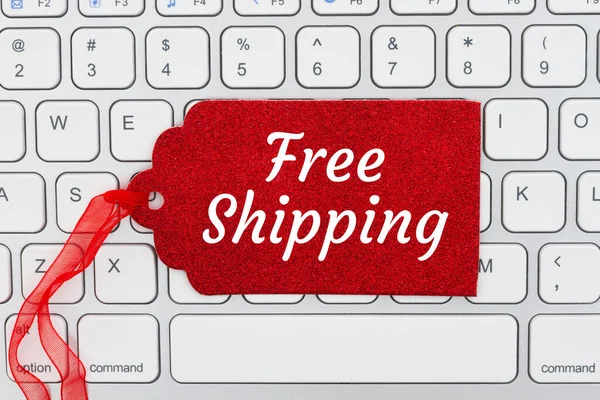 休日のオンラインショッピングメッセージのためのキーボードの赤いギフトタグ上の無料配送メッセージ — ストック写真