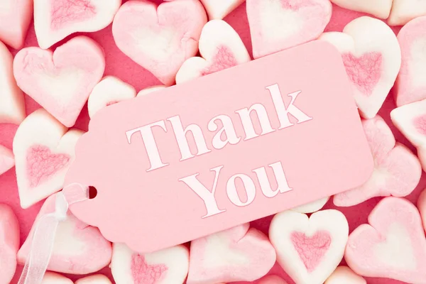 Thank you message on a pink gift tag with pink and white candy hearts for your valentine or anniversary message