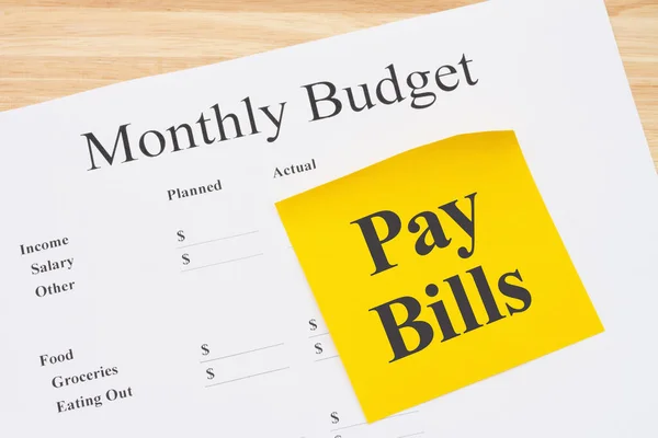 Reminder to pay bills with your monthly budget with a sticky note with on a desk