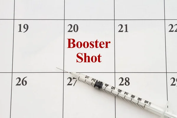Make an appointment to get your booster shot with a medical needle on a calendar