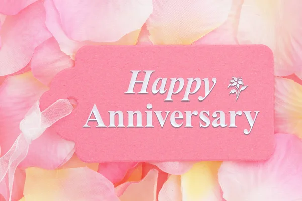 ピンクと黄色のバラの花びらとピンクのギフトのタグに幸せな記念日のメッセージ — ストック写真