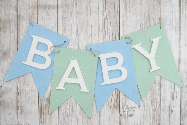 Blue and green baby banner sign on weathered wood