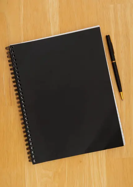 書くことまたはジャーナリングのための机のペンの背景が付いている黒いジャーナルのノートパッド — ストック写真