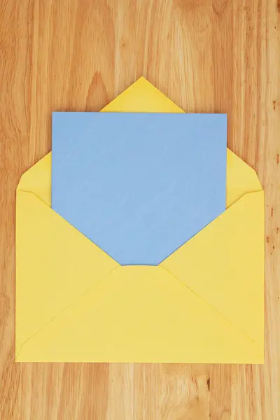 木桌上有黄色信封的空白贺卡 — 图库照片