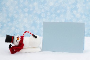 Snowman with hat and scarf and blank greeting card with snowflakes for holiday or Christmas message