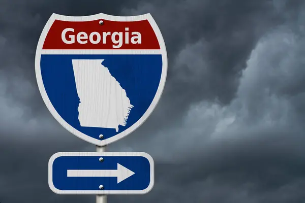 前往格鲁吉亚的路上 白色和蓝色的州际公路路标上印有 格鲁吉亚 格鲁吉亚地图上有暴风雨的天空背景 免版税图库图片