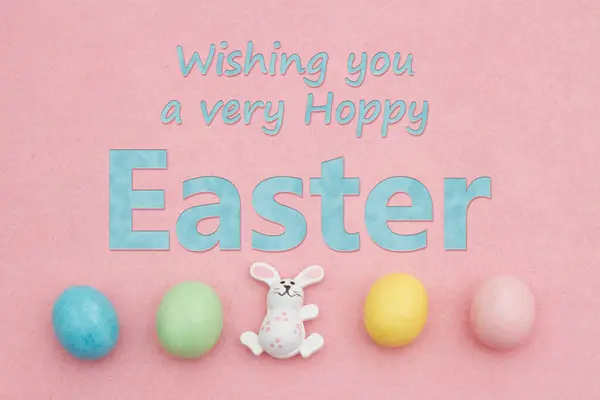 愿复活节的喜悦 伴随着淡淡的复活节的喜悦 还有粉色毛毡上的兔蛋 图库照片