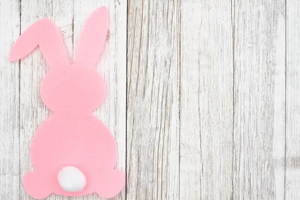 风化木材上的粉色复活节兔子背景 图库图片