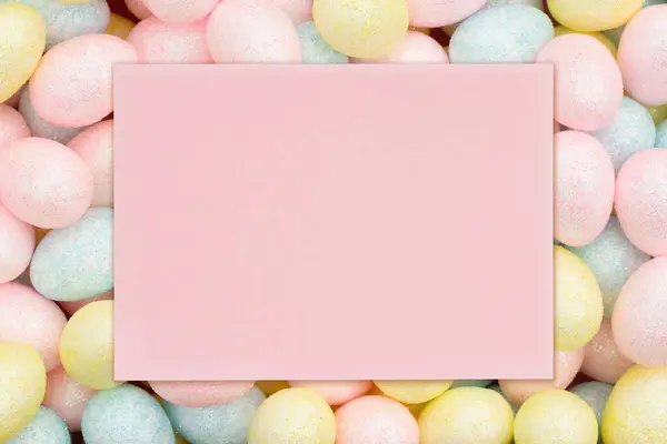 あなたのイースターや休日のメッセージのためのカラフルなパステルイースターエッグキャンディーと空白の淡いピンクの挨拶カード ロイヤリティフリーのストック画像