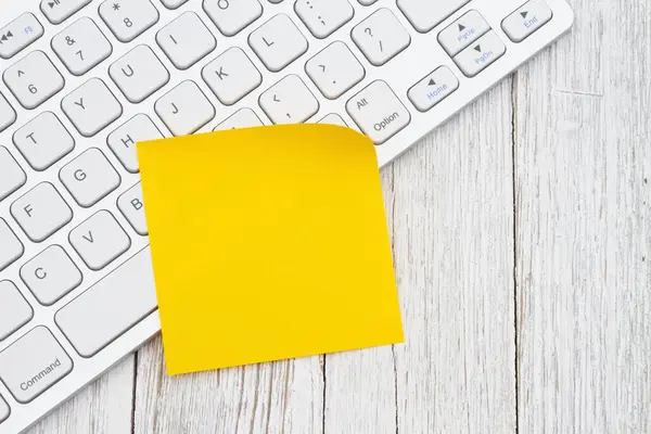 经风吹日晒的木桌上有黄色粘性注释的计算机键盘 免版税图库照片