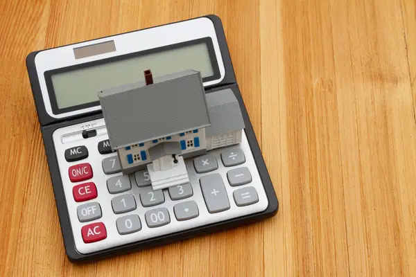 木桌上的房子和计算器 用来计算你的抵押贷款 图库图片