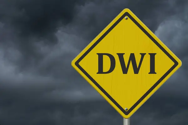 黄色警告Dwi道路标志与暴雨天 图库图片
