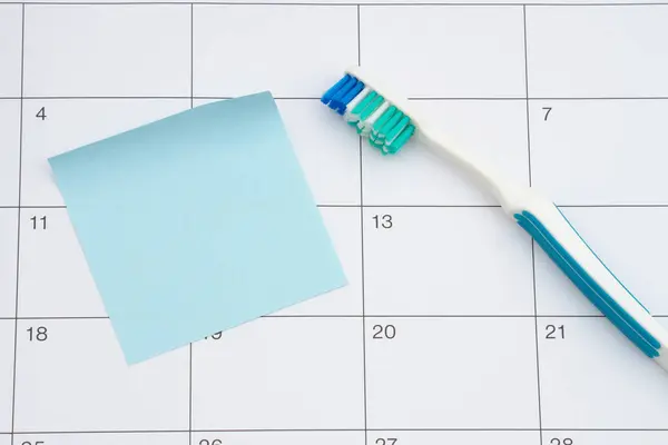カレンダーに歯ブラシと粘着性のあるノートで歯科検査の時間 ロイヤリティフリーのストック画像