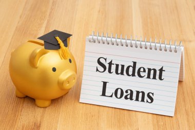 Öğrenci kredileri altın bir domuz kumbarası ve ahşap bir masa ve bir not defteri ile. 