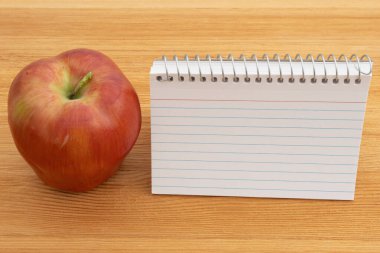 Back to School with a blank notebook and apple on a wood desk clipart