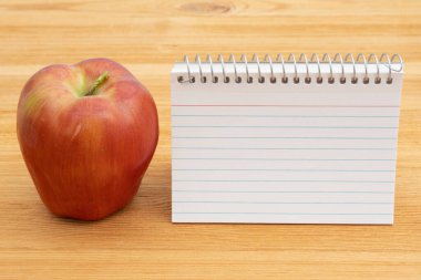 Back to School with a blank notebook and apple on a wood desk clipart