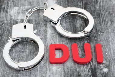 DUI message with silver handcuffs on weathered wood for your law related message clipart