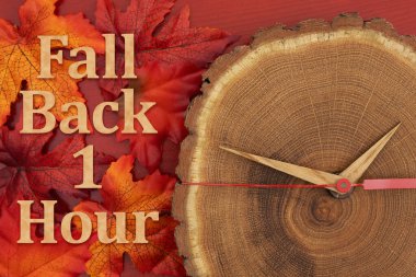 Bir saat geri git. Sonbahar yaprakları ve ahşap saat zaman değişimi için.
