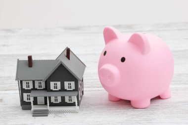 Mortgage payment with a pink piggy bank with a house on a wood desk clipart