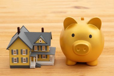 Mortgage payment with a gold piggy bank with a house on a wood desk clipart