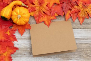 Sonbahar yaprakları ve balkabağı. Mevsimlik mesajınız için yıpranmış odunların üzerinde boş bir tebrik kartı.