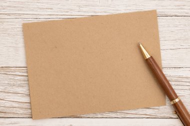 Boş kahverengi tebrik kartı ve yıpranmış ahşap masasında bir kalem.