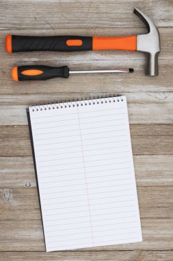 Portakal rengi tornavida, çekiç ve yıpranmış ahşap defter. 