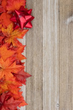 Mevsimlik mesajınız için yapraklar dökülür ve yıpranmış ahşap arka planda eğilir.