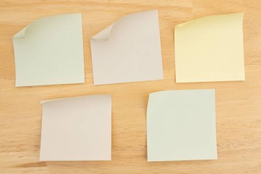 Ahşap bir masa yüzeyinin kenarları soyulmaya hazır renkli yapışkan notlar. Anımsatıcılar veya planlama görevleri için ideal.