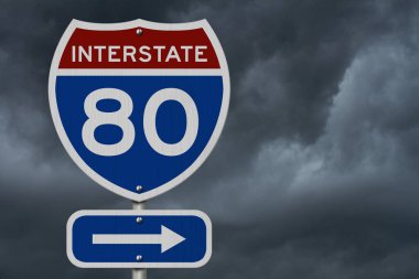 I-80 eyaletler arası kırmızı ve mavi yol işareti, fırtınalı arka planda.