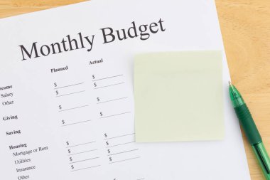 Yapışkan bir not ve yeşil kalemle aylık bütçe tablosu. Finansal planlama ve kişisel harcamaları yönetmek. Gelir ve giderleri düzenle.