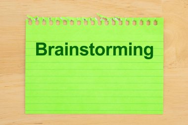 Çizgili kağıtlı yeşil not defteri ve kalın harflerle yazılmış beyin fırtınası. Planlama veya yaratıcılık kavramları için ideal.