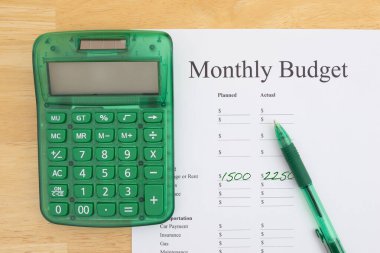Yeşil hesap makinesi ve kalem ile aylık bütçe belgesi finansal planlama ve para yönetimi için hazır.