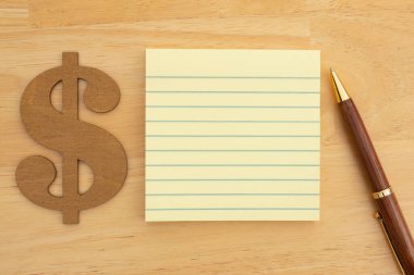 Boş bir not defteri ve kalemin yanında dolar sembolü. İş planlaması, bütçe ve finans konuları için mükemmel..