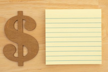 Bir altın dolar sembolü ve finansal notlar veya bütçe fikirleri yazmak için boş sarı çizgili bir not defteri. Finans kavramları için ideal.