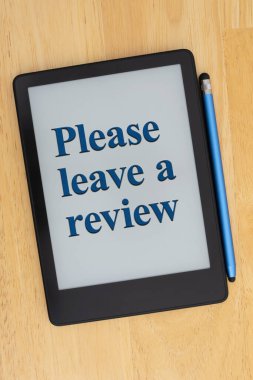 A digital e-reader displaying a message Please leave a review with a stylus on a wooden desk. Perfect for customer feedback concepts. clipart