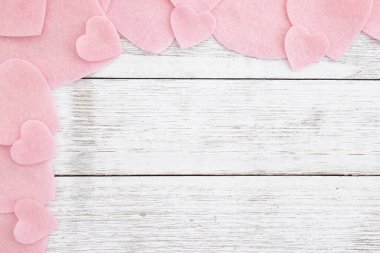 Yumuşak pembe kalpler, romantik, düğün ya da Sevgililer Günü tasarımları için ideal beyaz ahşap arka planda bir sınır oluşturuyor.