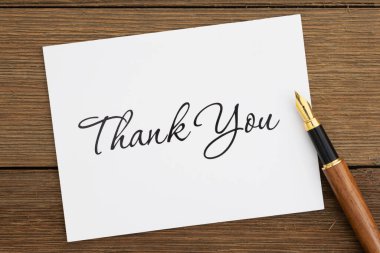 Thank you greeting card with a fountain pen on weathered wood desk