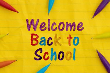 Akademik yıl ve yeni başlangıçlar için açık yaprak kağıtlı renkli kalemlerle okula hoş geldiniz.