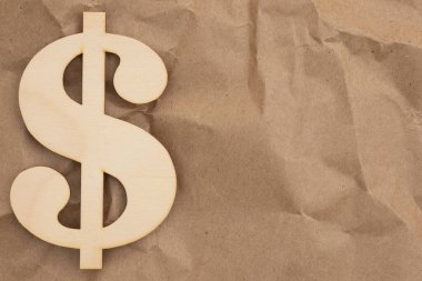 Para ve finansal temalar için buruşuk kahverengi ambalaj kağıdı arka planına sahip ahşap dolar sembolü